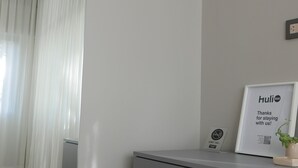 A hotel room with a grey filing cabinet, a framed sign on the wall, and a window with white curtains. - Double Queen Size with Private Bathroom (Mendoza)