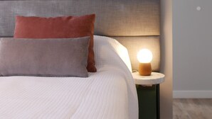 A neatly made bed with a white duvet and two pillows, a bedside table with a lamp, and a green wall. - Double Queen Size with Private Bathroom (Mendoza)