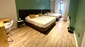 A hotel room with two beds, a small table, a chair, and a radiator. - Quadruple Room with Private External Bathroom (Mendoza)