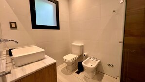 A modern bathroom with a large sink, toilet, bidet, and a mirror above the sink. - Quadruple Room with Private External Bathroom (Mendoza)