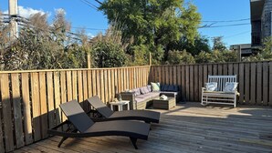 Eine Holzterrasse mit Liegestühlen, einer Sitzecke und einer Bank.
