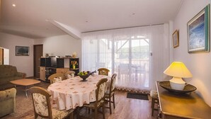 A dining area with a round table, chairs, a bowl of fruit, and a lamp on a side table.