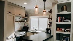 A modern kitchen with a central island, built-in appliances, and a bookshelf with books and decorative items.