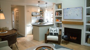 A modern kitchen with a central island, pendant lighting, and a fireplace.
