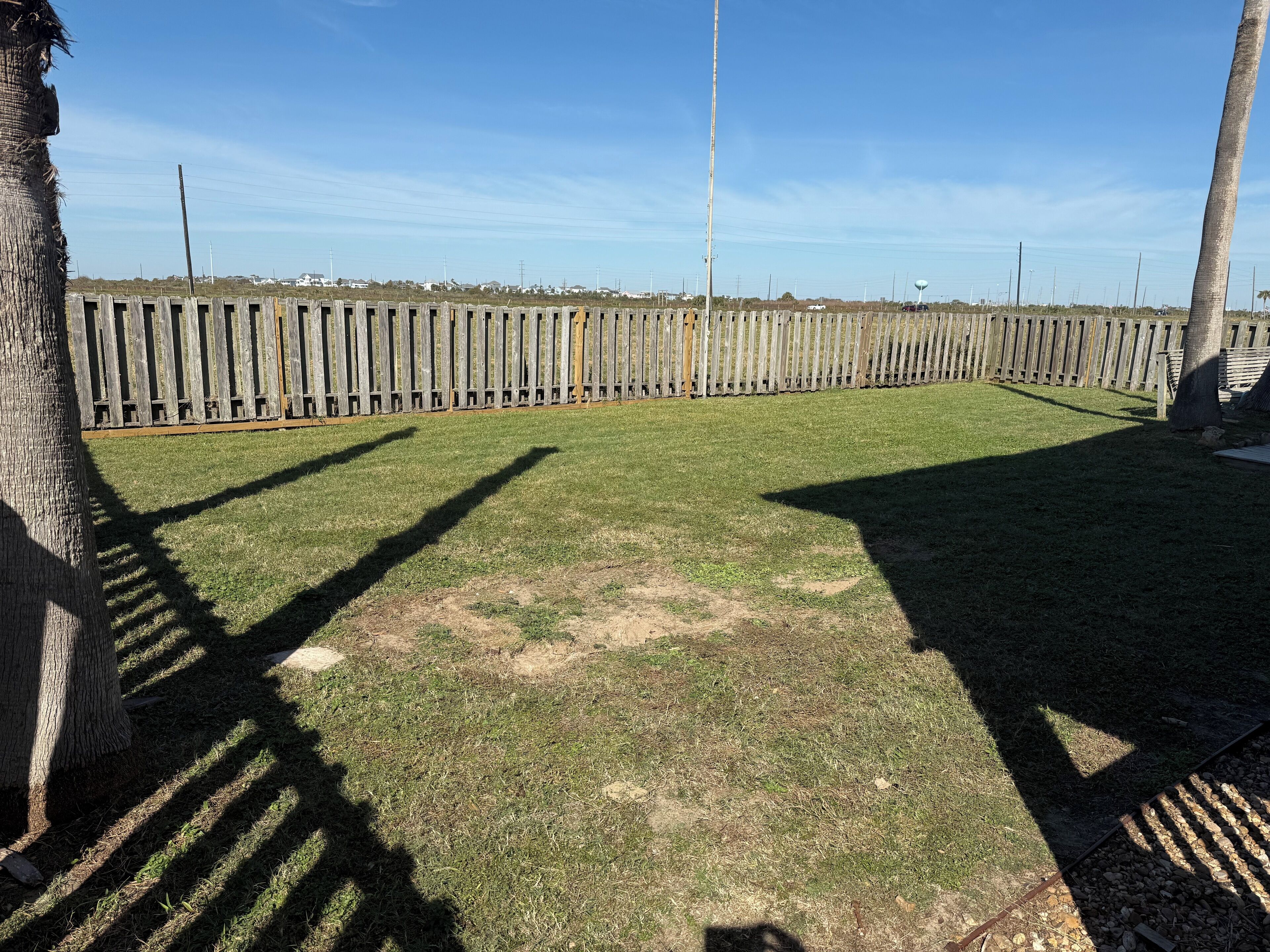 A fenced yard with a grassy area and a wooden fence.