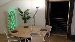 A dining area with a round wooden table, four chairs, a vase, and a plant. - Spacious apartment with magnificent view and terrace, on the 1st floor of a villa. (EMBRUN)
