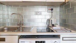 A modern kitchen with a stainless steel sink, a built-in oven, and a coffee machine.