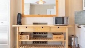 A kitchen area with a wooden countertop, a microwave, and a hanging light fixture.