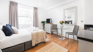Une chambre à coucher moderne avec un lit, une table de chevet et un bureau avec une chaise.