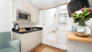 A compact kitchen with a microwave, sink, and a small dining area. - PBC | Studio Apartment in Bayswater (LS2) (London)