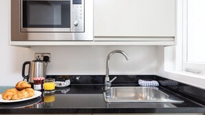 A modern kitchen with a stainless steel sink, a microwave, and a coffee maker. - PBC | Studio Apartment in Bayswater (LS2) (London)