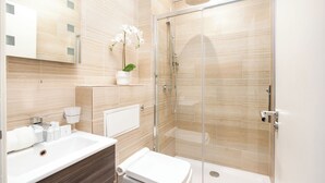 Ein modernes Badezimmer mit Duschkabine aus Glas, einem weißen Waschbecken und einer Toilette.