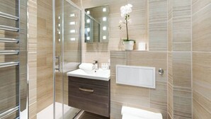 Une salle de bain moderne avec une douche à parois de verre, un meuble-lavabo avec un miroir et une orchidée en pot.