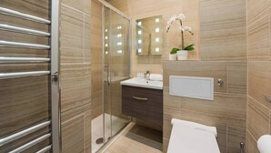 A modern bathroom with a glass shower enclosure, a vanity with a mirror, and a potted orchid. - PBC | Modern Studio in Bayswater LS10 (London)