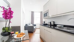 A modern kitchen with white cabinets, a black countertop, and a stainless steel sink. - PBC | Modern Studio in Bayswater LS10 (London)