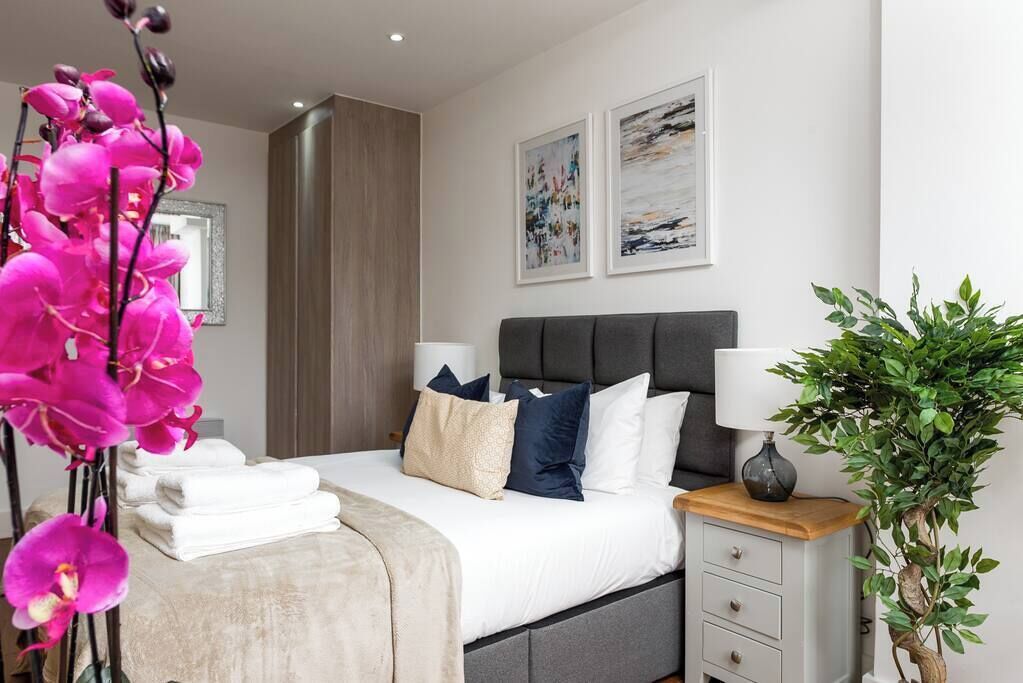 Een moderne slaapkamer met een bed, nachtkastjes en een groot raam.