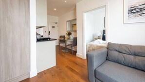 Ein modernes Apartment mit Küche, Essbereich und Wohnzimmer mit grauem Sofa.