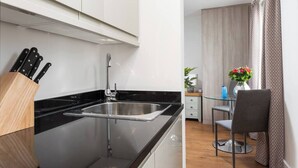 Una cocina moderna con encimera negra, pileta de acero inoxidable y un organizador de utensilios de madera.