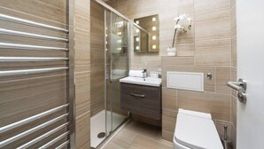 Un baño moderno con cabina de ducha de vidrio, tocador con espejo y inodoro.