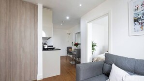 Una sala moderna con un sofá gris y un comedor al fondo.