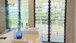 A modern bathroom with two sinks, a large mirror, and a view of a balcony with a metal railing. - Daintree Getaway is a secluded holiday home nestled in a private oasis (Lower Daintree)