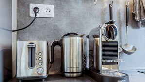 A kitchen with a toaster, a coffee maker, and a kettle on the counter. - Spacious loft Luxembourg Garden (Paris)