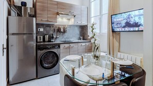 A modern kitchen with stainless steel appliances, wooden cabinets, and a glass dining table set for four. - Spacious loft Luxembourg Garden (Paris)