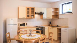 Una cocina funcional con mesa, microondas, estufa y una ventana con cortinas.