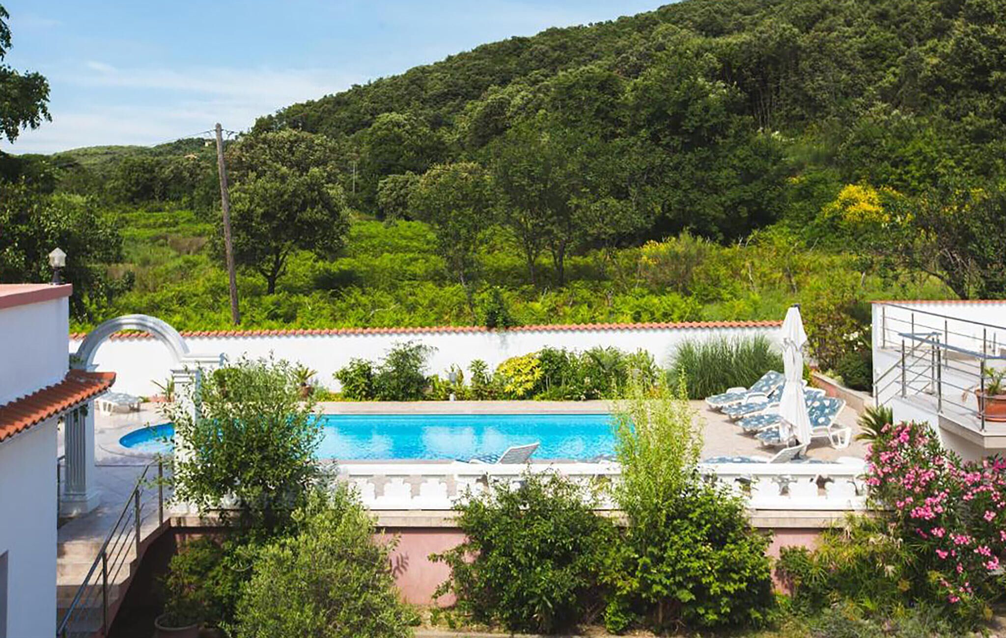 A pool area with a view of a lush green hillside.