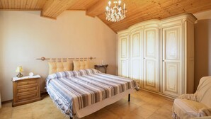 A bedroom with a bed, a nightstand, a lamp, a clock, and a wardrobe.