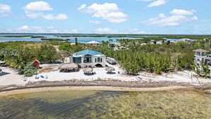 A beachfront property with a large house, a pool, and a clear view of the ocean and islands in the distance.