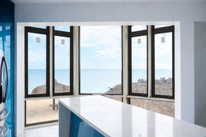 A room with a large window overlooking a beach, a white countertop, and a blue wall. - Star Room Barnacle Resort (Big Pine Key)