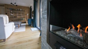 A modern living room with a fireplace, wooden flooring, and a sofa.