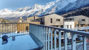 A modern building with a glass balcony overlooking a snowy mountain range.