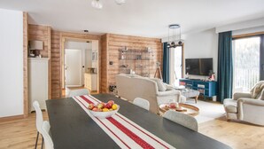 A modern living room with a dining table, sofa, and TV.