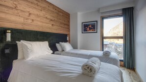 A hotel room with two beds, wooden headboard, a framed picture on the wall, and a window with curtains.