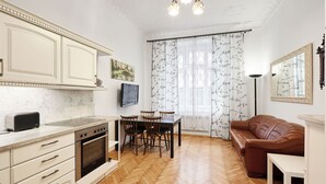 A kitchen with a stove, oven, and a dining area with chairs and a table. - Central & Parking Assistance (Prague)