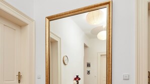 A hallway with a large mirror on the wall, wooden flooring, and a door on the left. - Central & Parking Assistance (Prague)