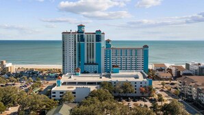 A hotel with multiple high-rise buildings, a parking area, and a beachfront view.