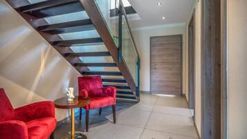 Ein modernes Interieur mit Treppe, roten Samtstühlen und einem kleinen Tisch mit einer Dekoration.