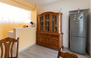 Functional kitchen with a wooden cabinet, stainless steel refrigerator, and light-colored countertop.