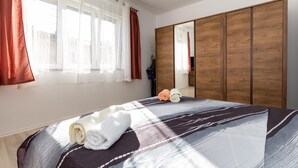 Een hotelkamer met een groot bed, een houten garderobe en een raam met gordijnen.