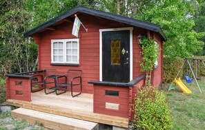 A small wooden cabin with a black door, a window, and a porch with metal chairs. - 1 bedroom beautiful home in Stockholm (Stockholm)