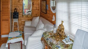 Une pièce chaleureuse avec un canapé blanc, une petite table recouverte d’une nappe à motifs floraux et une lampe décorative.