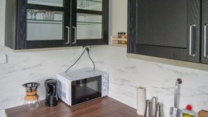 Une cuisine équipée d’un four à micro-ondes, d’une machine à café et de divers ustensiles de cuisine.