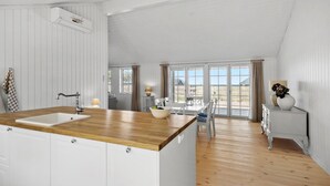 Een ruime keuken met een houten aanrecht, witte kastjes en een groot raam met uitzicht op de omgeving.