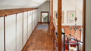 Eine Holztreppe mit Handlauf, die zu einer Zwischenebene mit Holzboden und einem Streifen Teppich führt.