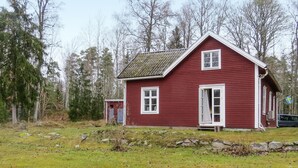 Ein rotes Holzhaus mit Satteldach, einer Haustür und einer kleinen Veranda.