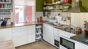 Eine Küche mit weißen Schränken, einer Holz Arbeitsplatte, einem Spülbecken und einem Herd.