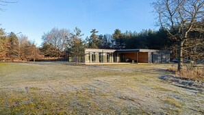 Un bâtiment moderne doté de grandes fenêtres en verre, d’un toit plat et d’un espace extérieur abrité.